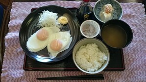 Comida tradicional japonesa con arroz, dos huevos, verduras ralladas y un tazón pequeño de sopa sobre una bandeja.