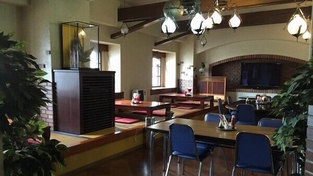 Un restaurante con chimenea de ladrillo, vigas de madera y lámparas colgantes.