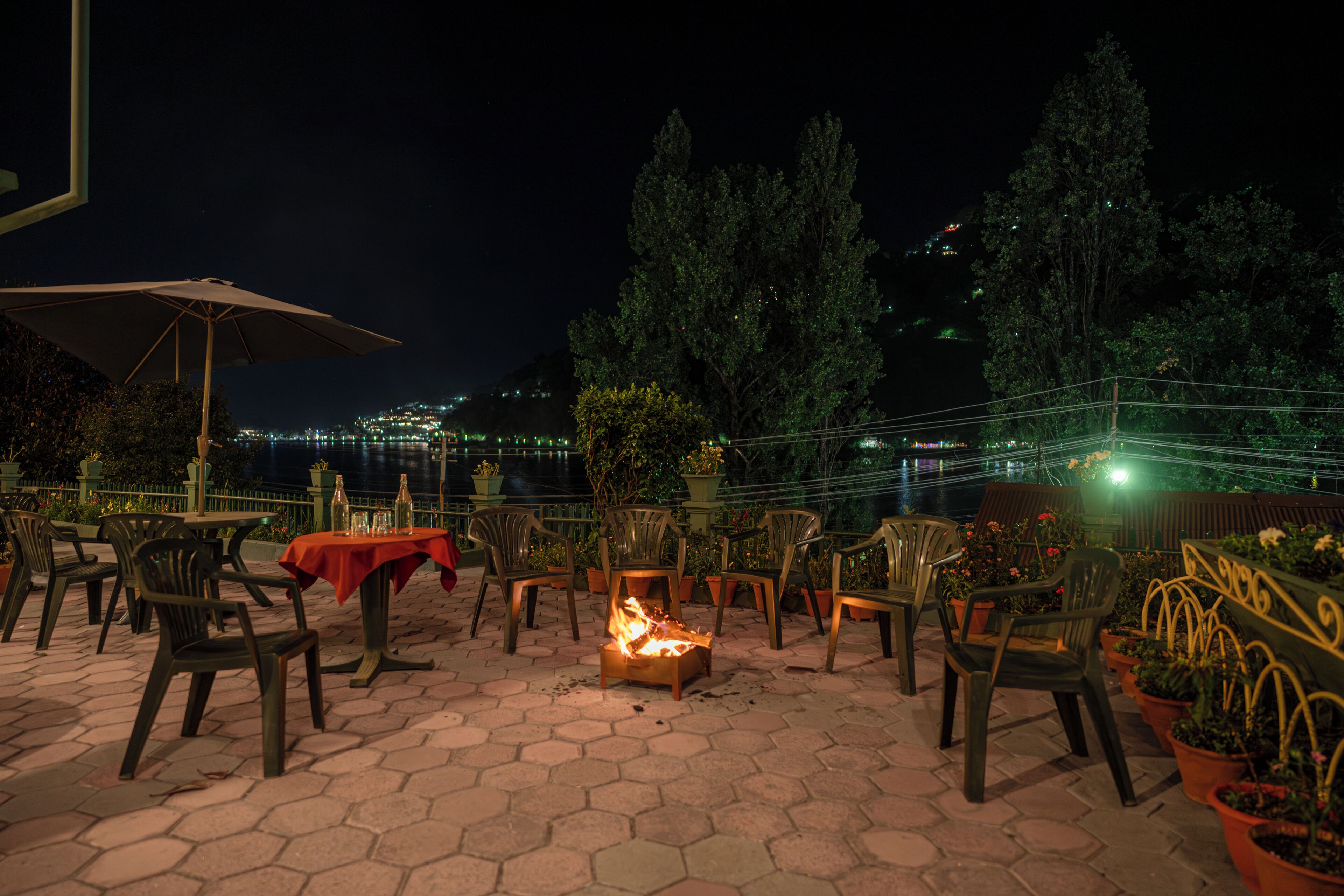 An outdoor patio with hexagonal tiles, chairs, tables, and a fire pit.