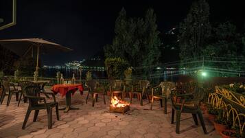 An outdoor patio with hexagonal tiles, chairs, tables, and a fire pit.