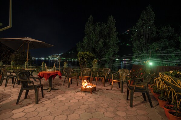 Un patio exterior con baldosas hexagonales, sillas, mesas y un pozo de fuego.