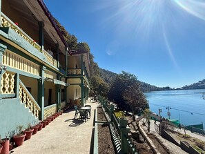 A building with a balcony, outdoor seating, and a view of a body of water. - The Grand Hotel Nainital (Nainital)