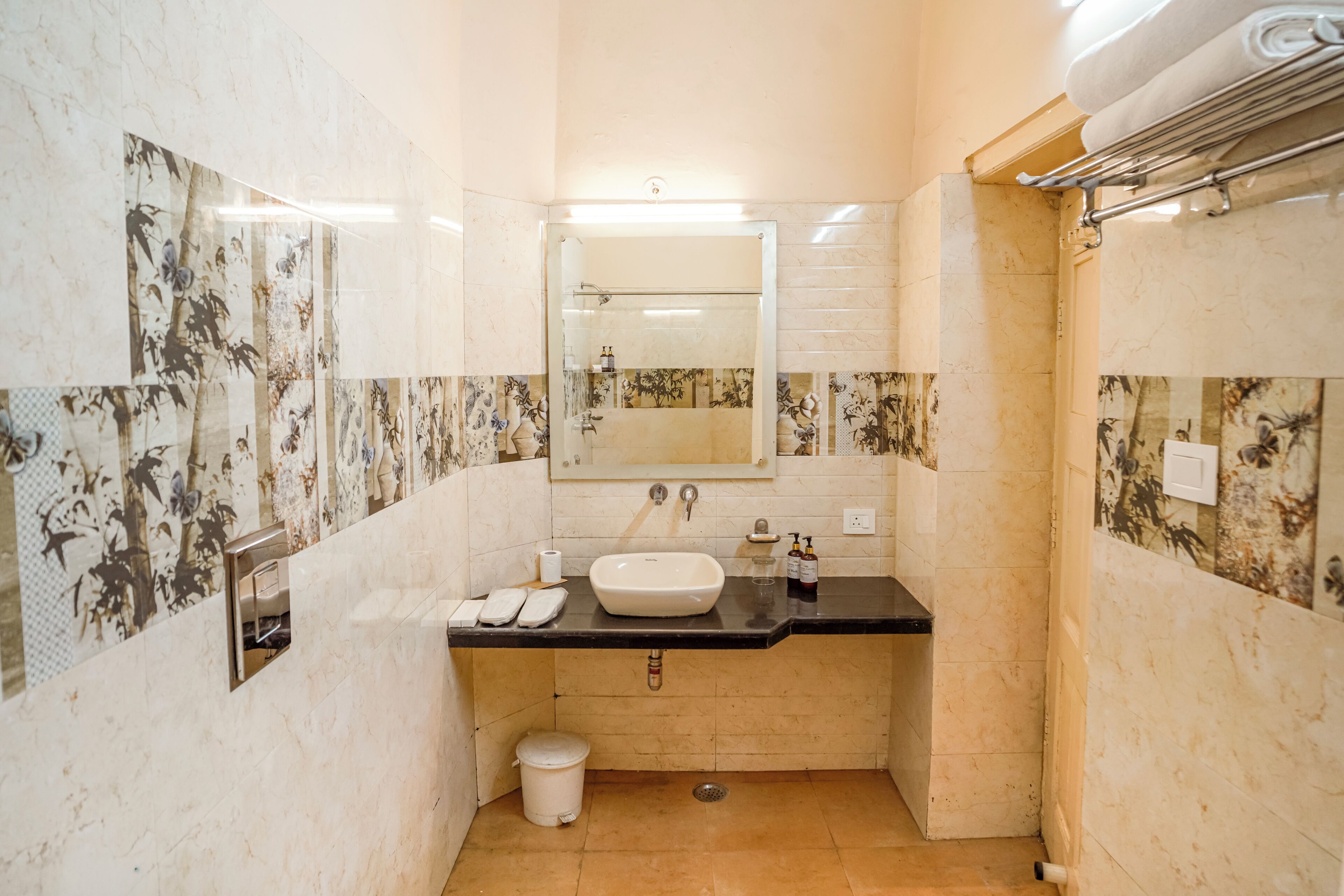 Un baño con lavamanos, espejo y toallero.