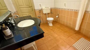 Un baño con lavamanos negro, inodoro blanco y azulejos color beige.