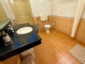 A bathroom with a black sink, white toilet, and beige tiles. - The Grand Hotel Nainital (Nainital)