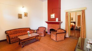 A room with a sofa, armchairs, a coffee table, a fireplace, and framed pictures on the wall. - The Grand Hotel Nainital (Nainital)