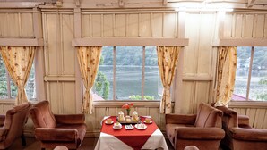 A room with a table set for tea, two armchairs, and a sofa. - The Grand Hotel Nainital (Nainital)