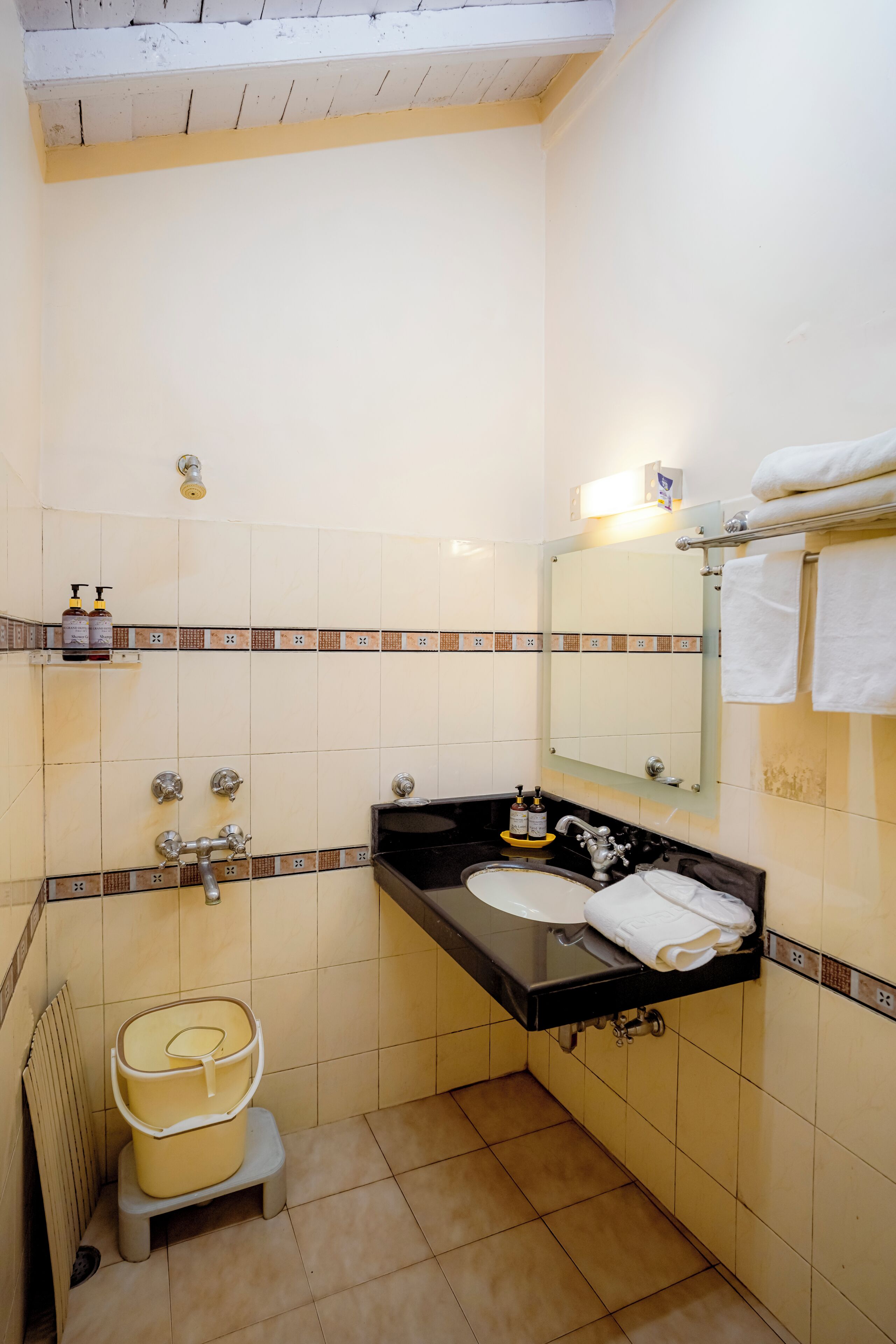 A bathroom with a sink, mirror, towel rack, and a toilet with a lid.