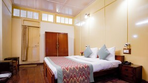 A bedroom with a bed, wooden wardrobe, bedside table, and a nightstand. - The Grand Hotel Nainital (Nainital)