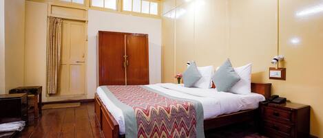 A bedroom with a bed, wooden wardrobe, bedside table, and a nightstand.