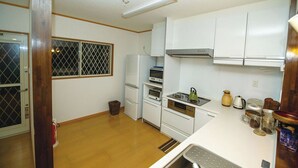 Uma cozinha compacta com armários brancos, um fogão e um micro-ondas.