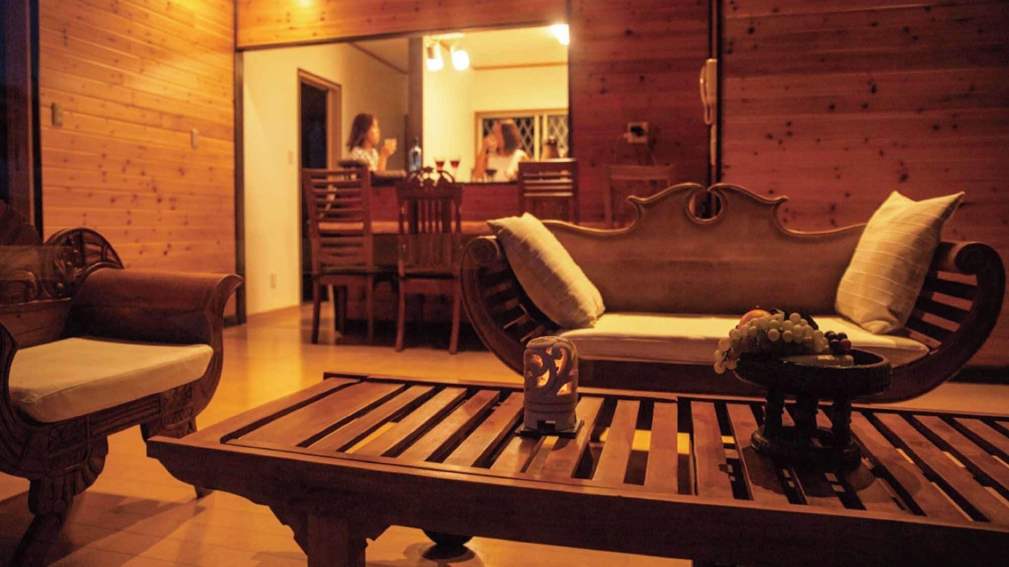 A cozy room with a wooden bench, a cushioned sofa, and a dining area in the background.