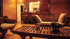A cozy room with a wooden bench, a cushioned sofa, and a dining area in the background.