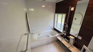 A modern bathroom with a bathtub, a shower, a window, and a mirror.