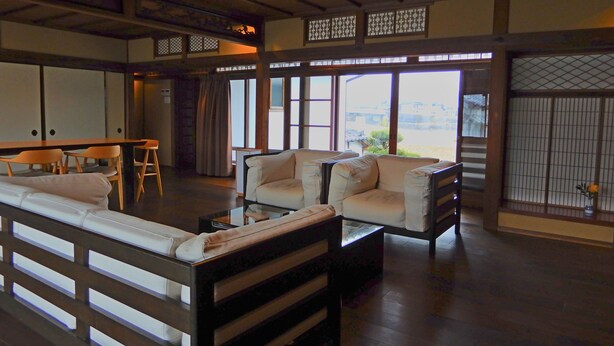 Een traditionele Japanse kamer met tatami vloerbedekking, een lage tafel en een bank.