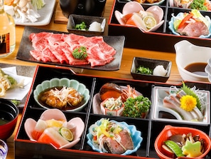 Une variété de plats japonais présentés sur une table en bois, notamment des sashimis, des sushis et d’autres mets délicats.