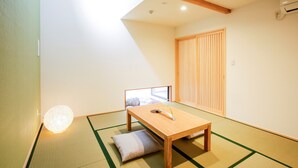 Ein traditioneller japanischer Raum mit Tatami-Böden, einem niedrigen Holztisch, einem Kissen und einer Schiebetür.