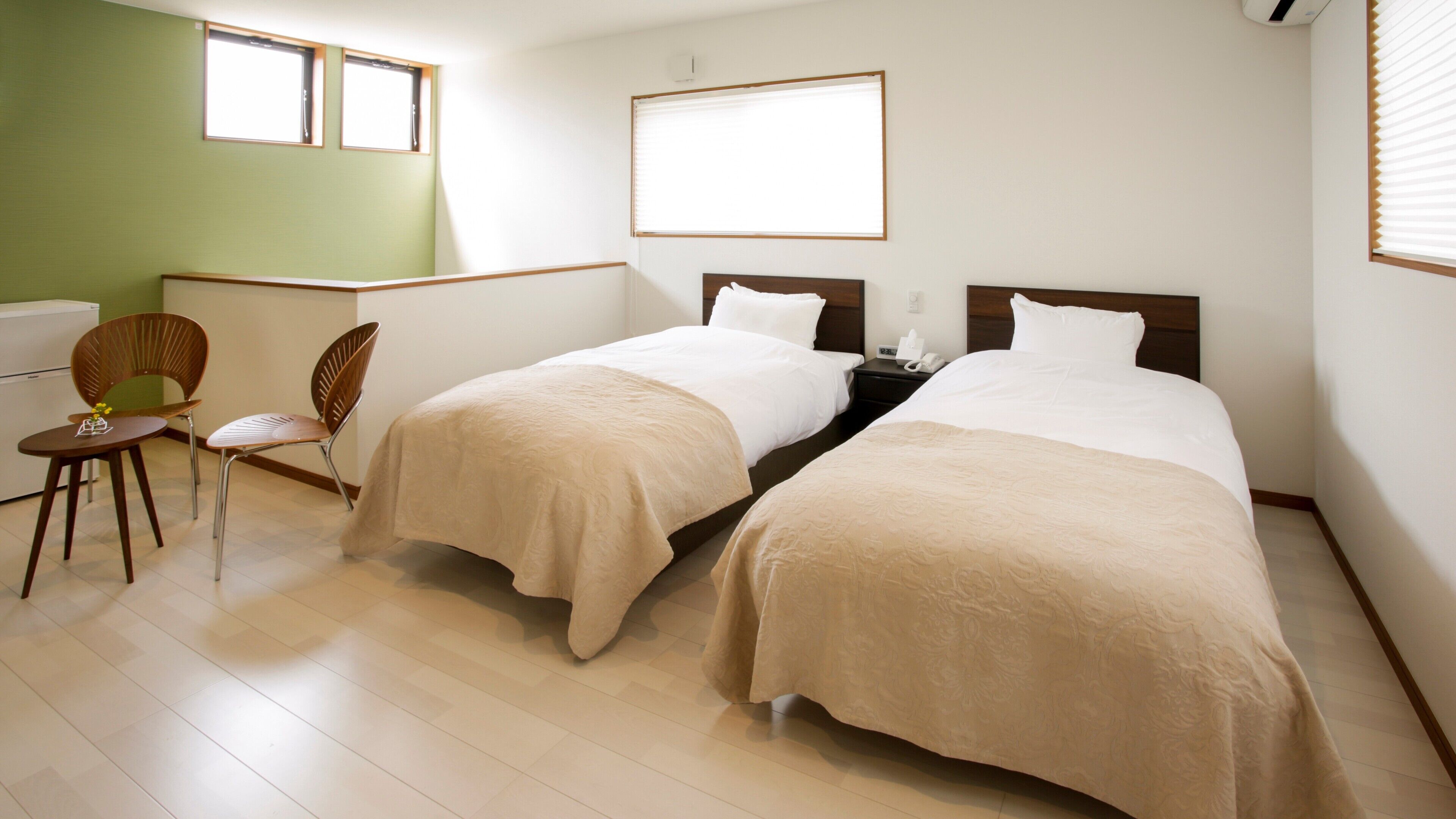 Une chambre d’hôtel avec deux lits, un bureau et une chaise.