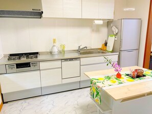 A modern kitchen with white cabinetry, a gas stove, a sink, and a refrigerator. - Palm Villa Ishigakijima Yugafu (Ishigaki)