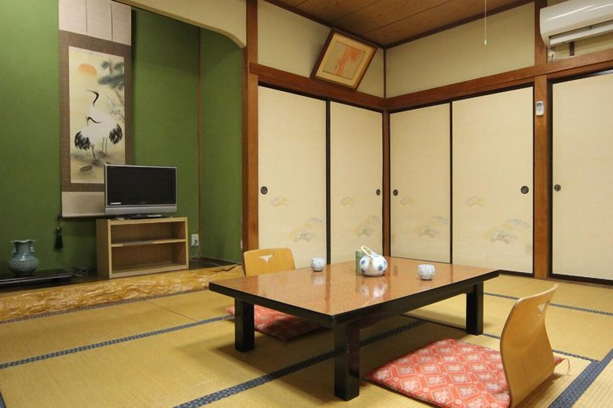 Una habitación japonesa tradicional con suelo de tatami, una mesa baja y puertas correderas.
