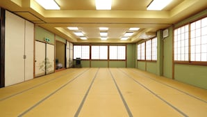 A tatami mat room with sliding doors, a television, and a green exit sign. - Minshuku Sampo (Chichibu)