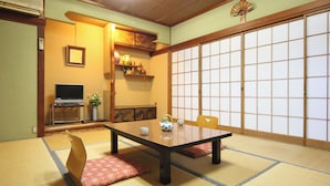 A traditional Japanese room with tatami flooring, a low table, a television, and a shoji screen. - Minshuku Sampo (Chichibu)