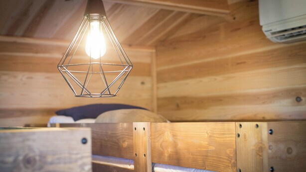 A wooden cabin interior with a bed and a hanging light fixture. - Manazuru Glamping & BBQ Coottage Deja Vu (Manazuru)