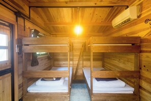 Eine Holzhütte mit Stockbetten, einem Fenster und einer Klimaanlage.