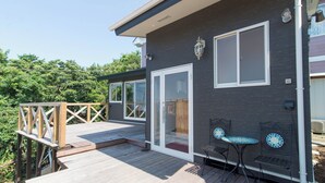 A deck with a wooden railing, a glass door, and a small table with chairs. - Manazuru Glamping & BBQ Coottage Deja Vu (Manazuru)