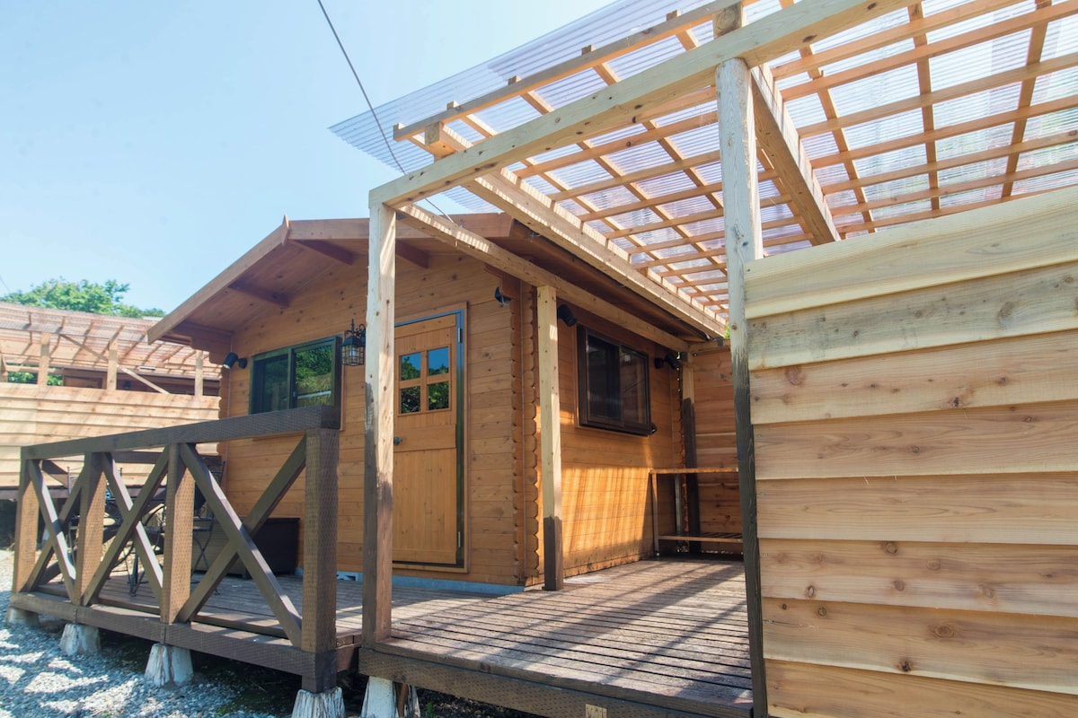A wooden cabin with a covered porch, a door, and a window.