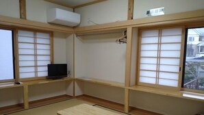 A traditional Japanese room with tatami flooring, a small wooden table, a TV on a low shelf, and shoji screens. - Marutomiso (Fujikawaguchiko)