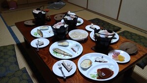 Uma mesa de jantar com diversos pratos e utensílios, cercada por esteiras de tatame.