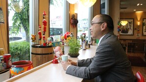 A man seated at a table with a variety of items including a plant, a red cup, and a small figurine. - Shizuoka Hotel Tokinosumika (Shizuoka)