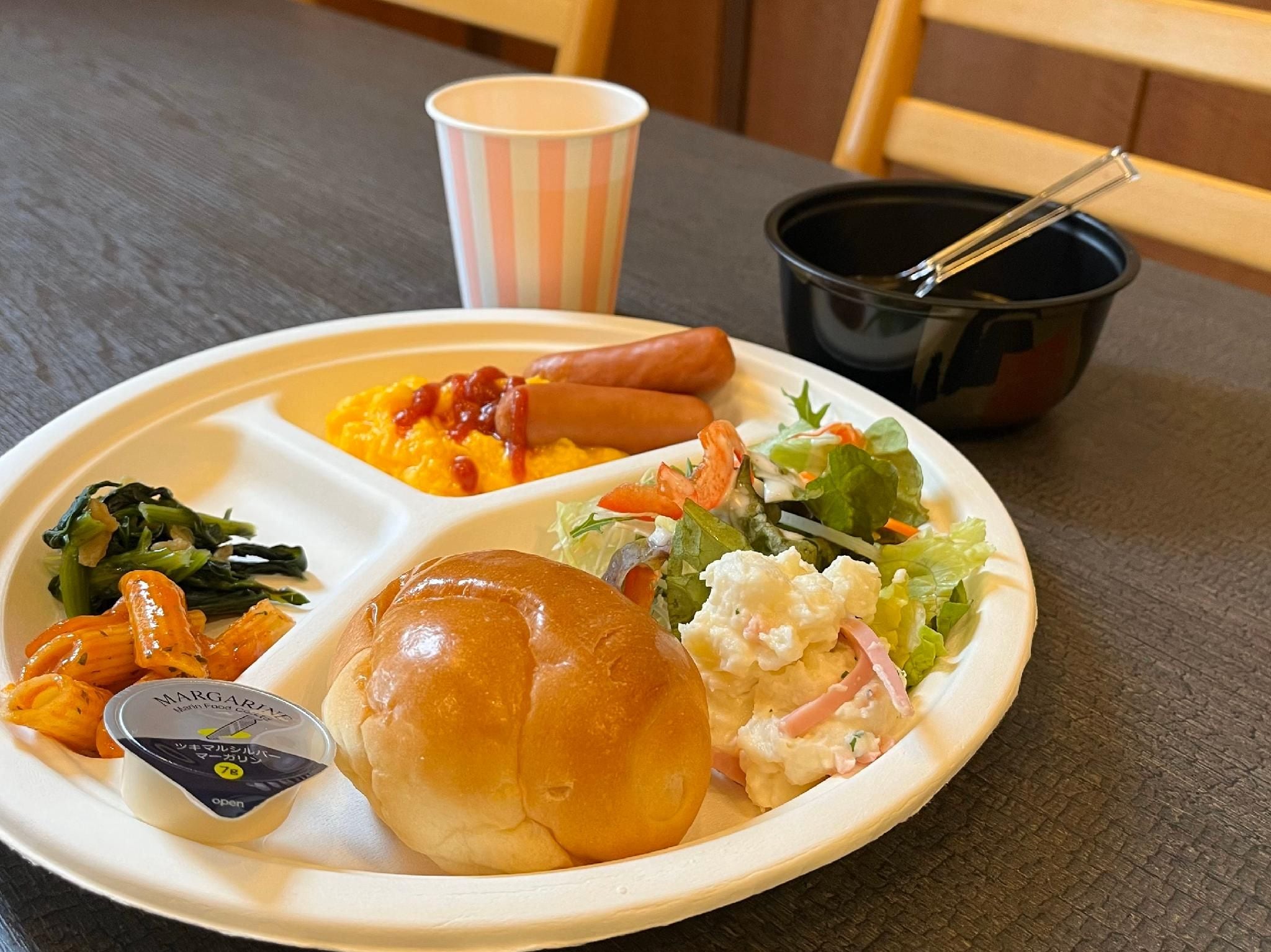 A meal with a variety of food items including a hot dog, macaroni salad, coleslaw, and a sandwich on a paper plate.