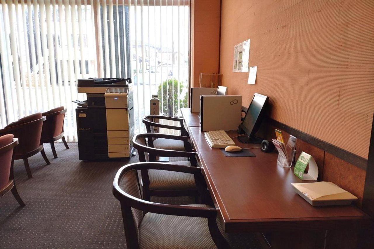 A conference room with a long table, several chairs, a computer, and a printer.