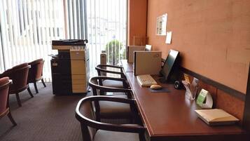 A conference room with a long table, several chairs, a computer, and a printer.