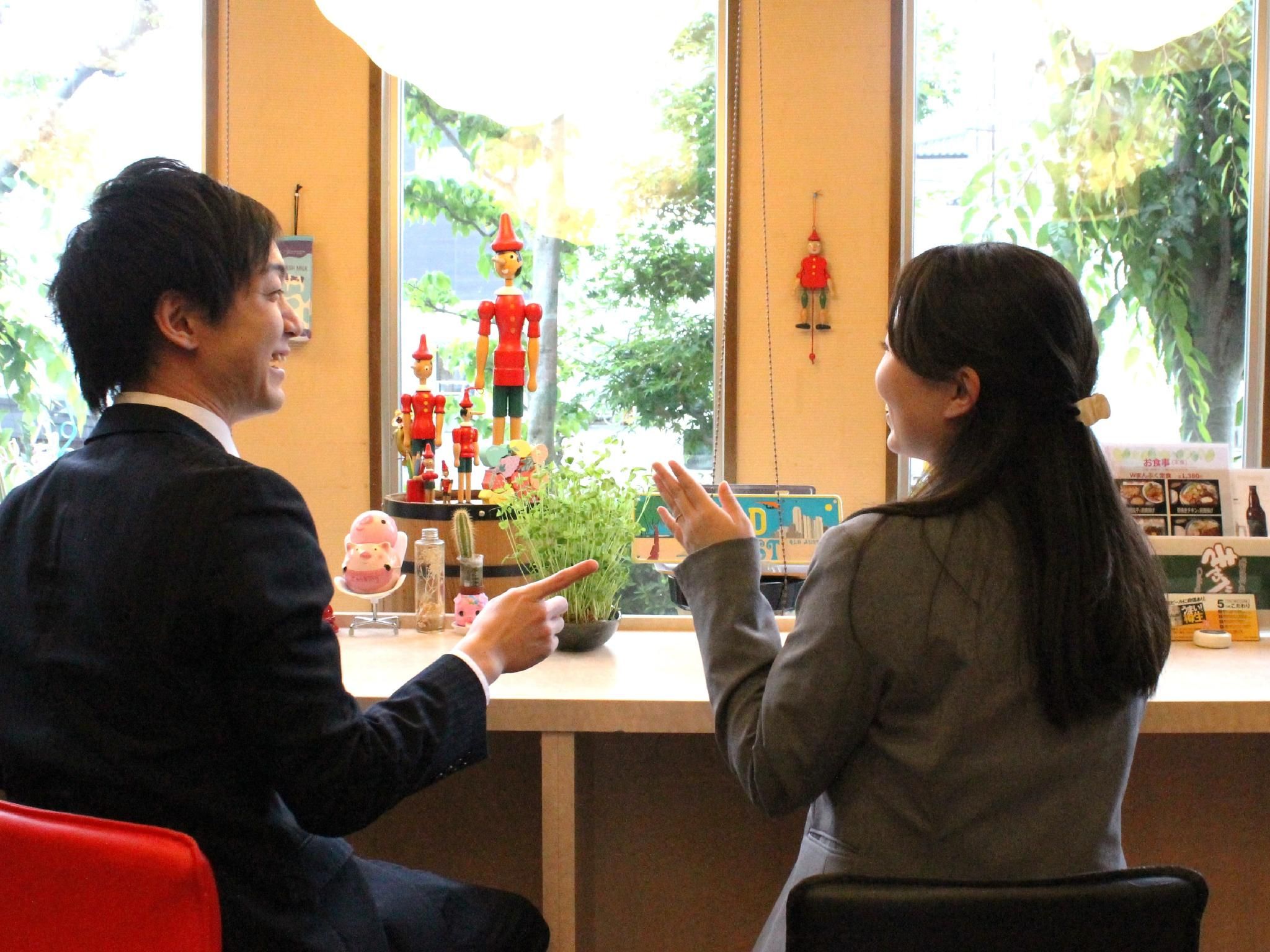 A man and a woman sitting at a counter with a view of greenery outside.