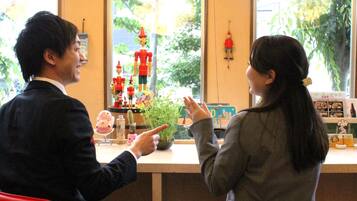 A man and a woman sitting at a counter with a view of greenery outside.