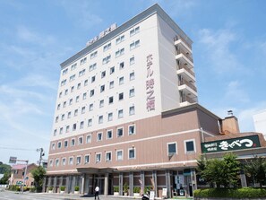 Um hotel com vários andares, fachada plana, várias janelas e entrada no nível da rua com uma placa.