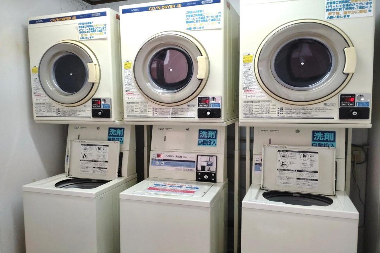 Three rows of identical front-loading washing machines with control panels and instruction manuals.