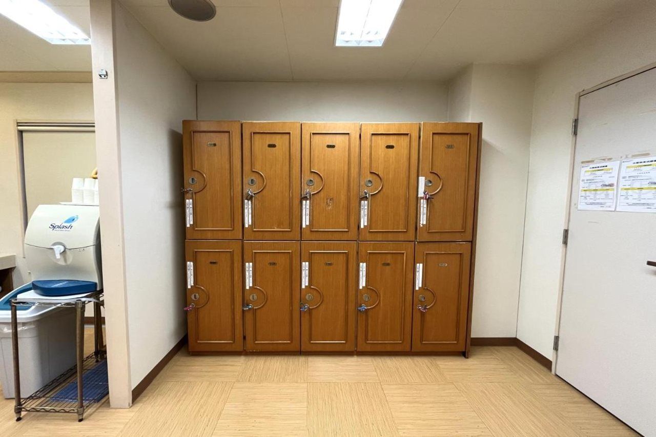 A restroom with wooden lockers, a hand dryer, and a paper dispenser.