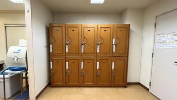 A restroom with wooden lockers, a hand dryer, and a paper dispenser.