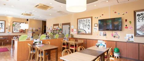A restaurant interior with wooden furniture, a central counter, and wall decorations.