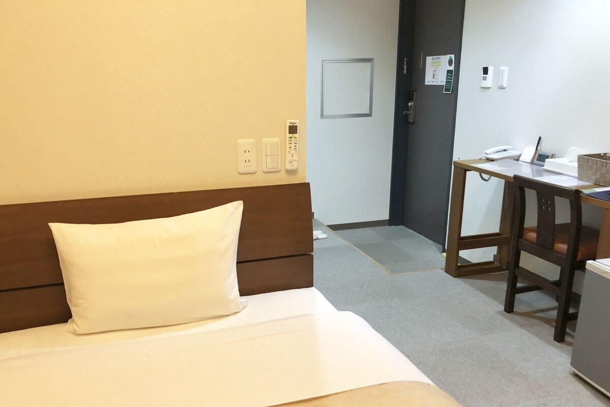 A hotel room with a bed, a desk, and a chair.