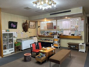 A room with a reception desk, a refrigerator, a wooden bench, and a small table with chairs. - Urugi Sasayuriso (Urugi)