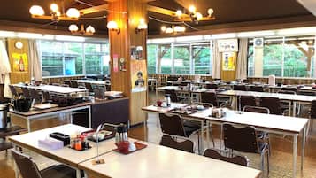 Comedor con varias mesas y sillas, detalles de madera y amplios ventanales que dejan entrar luz natural.