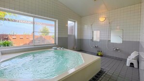 Ein Badezimmer mit einer großen Badewanne, einer Dusche und einem Fenster mit Blick nach außen.