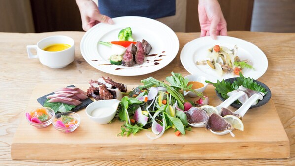 A wooden table with various dishes, including meat, vegetables, and seafood, and a cup of coffee. - Pension Turning Point (Awaji)