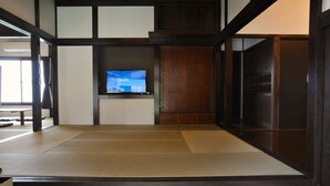 Tatami-mattoilla päällystetty huone, jossa on televisio puisen jalustan päällä.