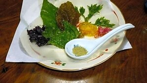 A plate with various food items and a spoon on a table.
